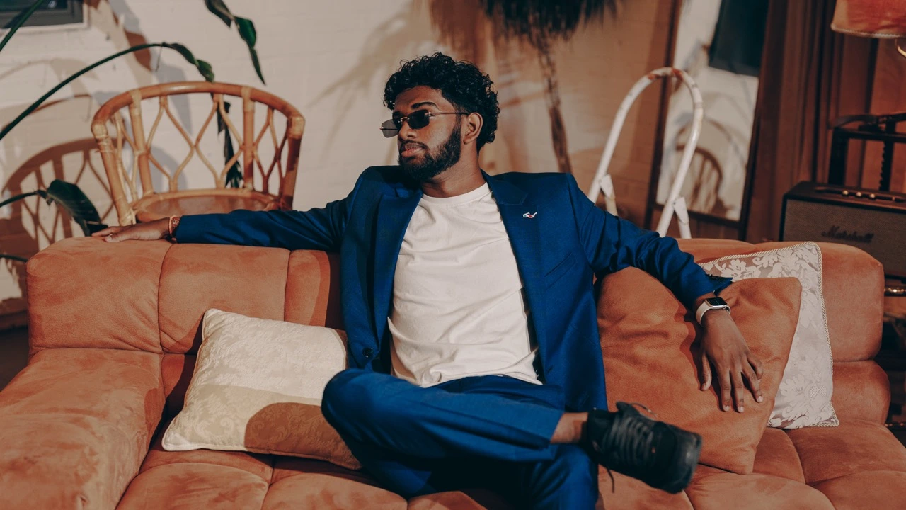 DJ Clickz seated in a blue suit